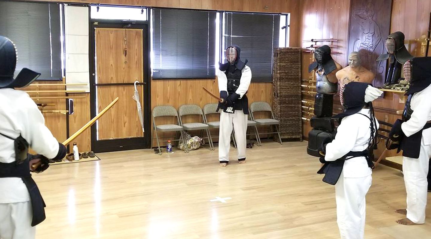 A kendo class in the training hall, students in armor with bamboo swords